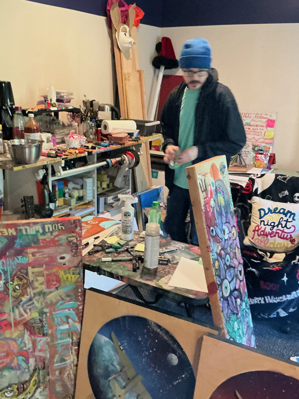 Jason Breish standing in his art studio surrounded by colorful paintings